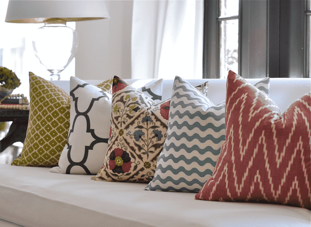 imagen de almohadones de colores y estilos diversos en un sillon blanco en el living de una casa